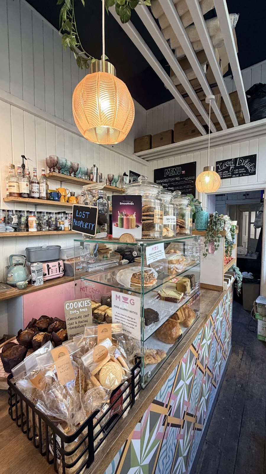 Along the tiled counter past the cake and pastry display, pendant light overhead