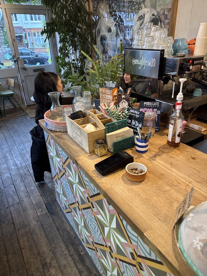 The tiled counter with plants and stock, staff serving at the far end